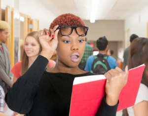 a high school girl raises her glasses in shock while reading the yearbook in the hallway
