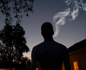 todd marinovich's silhouette stands naked and smoking in a strangers yard at night