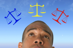 a man ponders over blue, yellow, and red legal scales in front of a blue sky